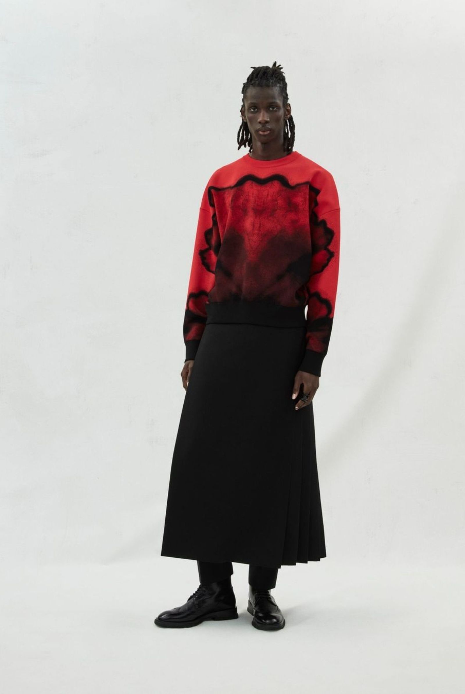 McQueenMenAW23 black ink flower jacquard red jumper with a black kilt and cigarette trousers.