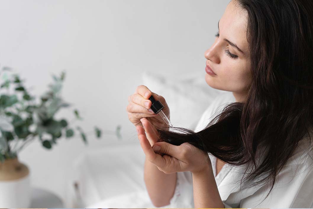 A woman adding hair product on her hair.