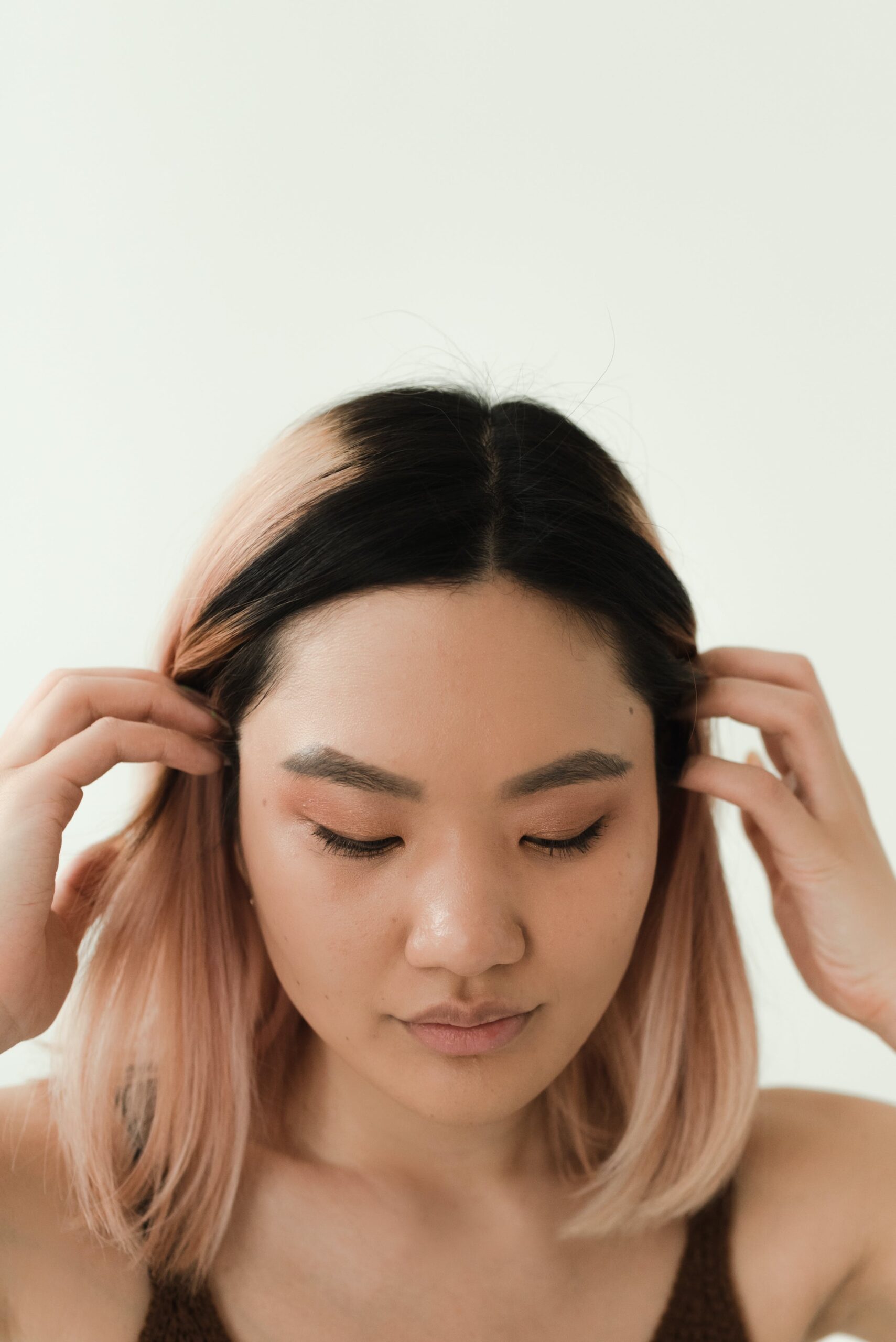 A woman with colored hair brushing her hair to the side with her fingers.