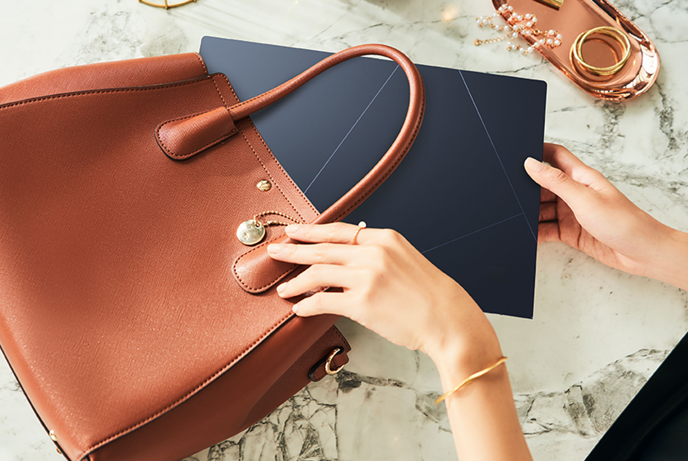 The ASUS Zenbook 14 OLED placed inside a brown handbag
