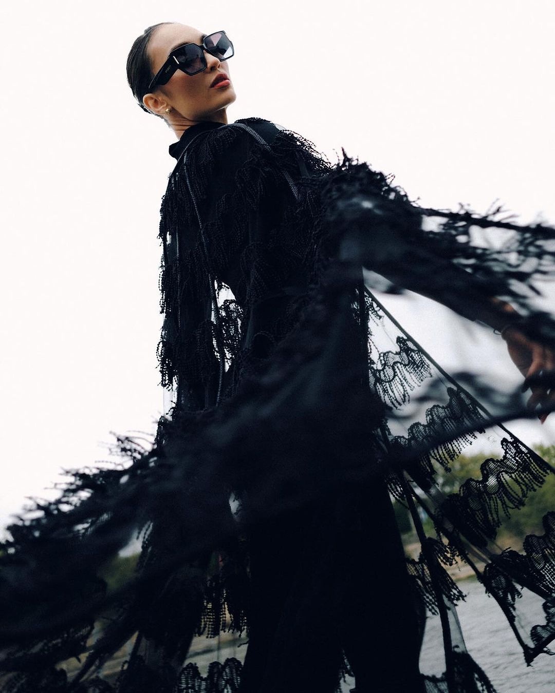 R'Bonney Gabriel in an all-black ensemble, ,featuring a lacy, textured cape on her shoulders for Florentina Letner's show