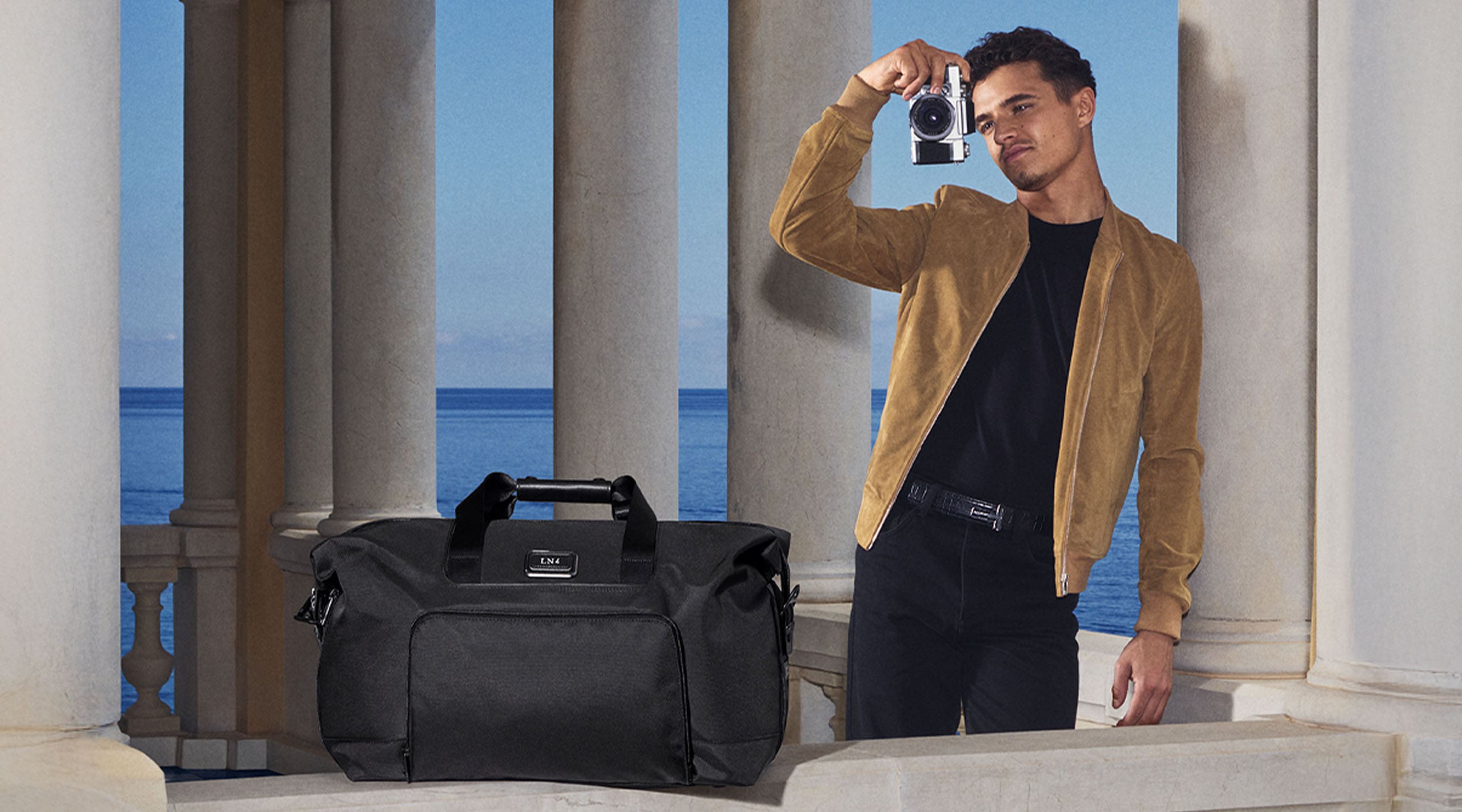 F1 McLaren Driver and longtime TUMI Global Ambassador Lando Norris with the TUMI Turin handbag at this side