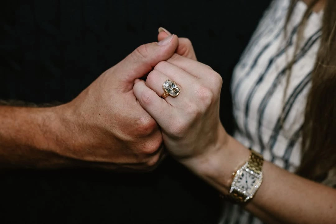 Victorian-inspired ring with an 8-carat, cushion-cut diamond, handcrafted in 18k yellow gold, and adorned with smaller diamonds and hand-engravings. Co-designed by Travis Kelce and Kindred Lubeck.