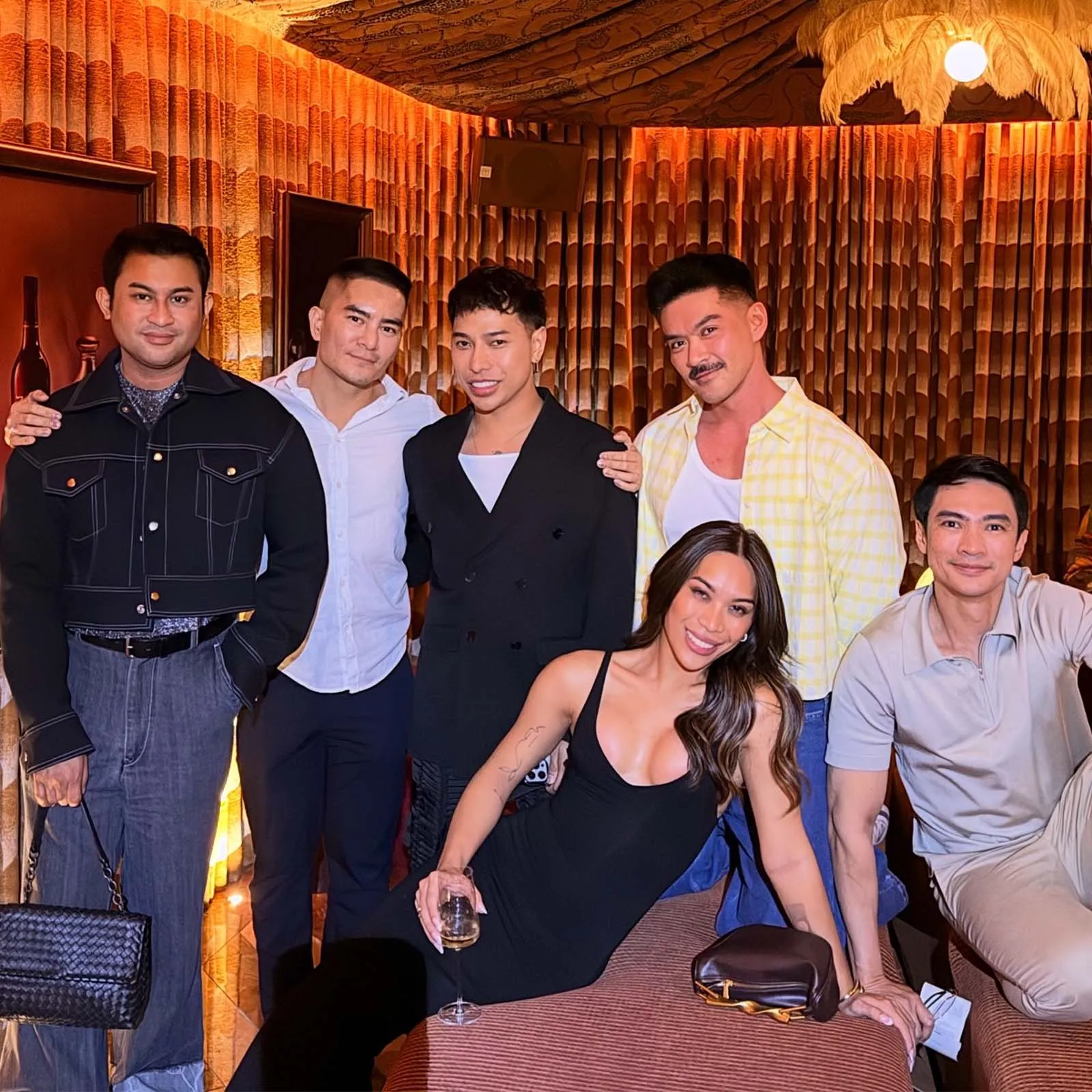 Group of friends posing for a photo at a stylish indoor party, smiling and standing together.