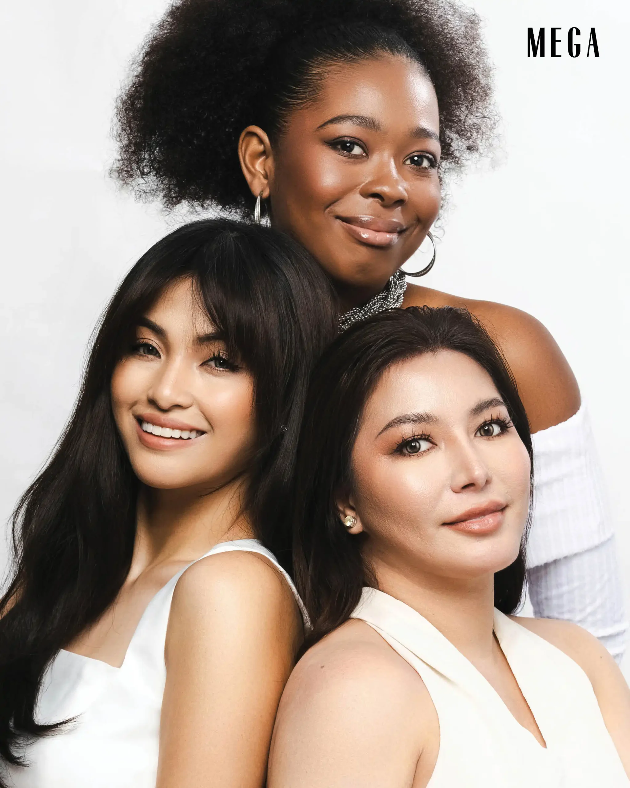 Three smiling women posing together for a portrait against a white background, showcasing diversity (one in front left, one behind).MEGA logo in top-right corner.