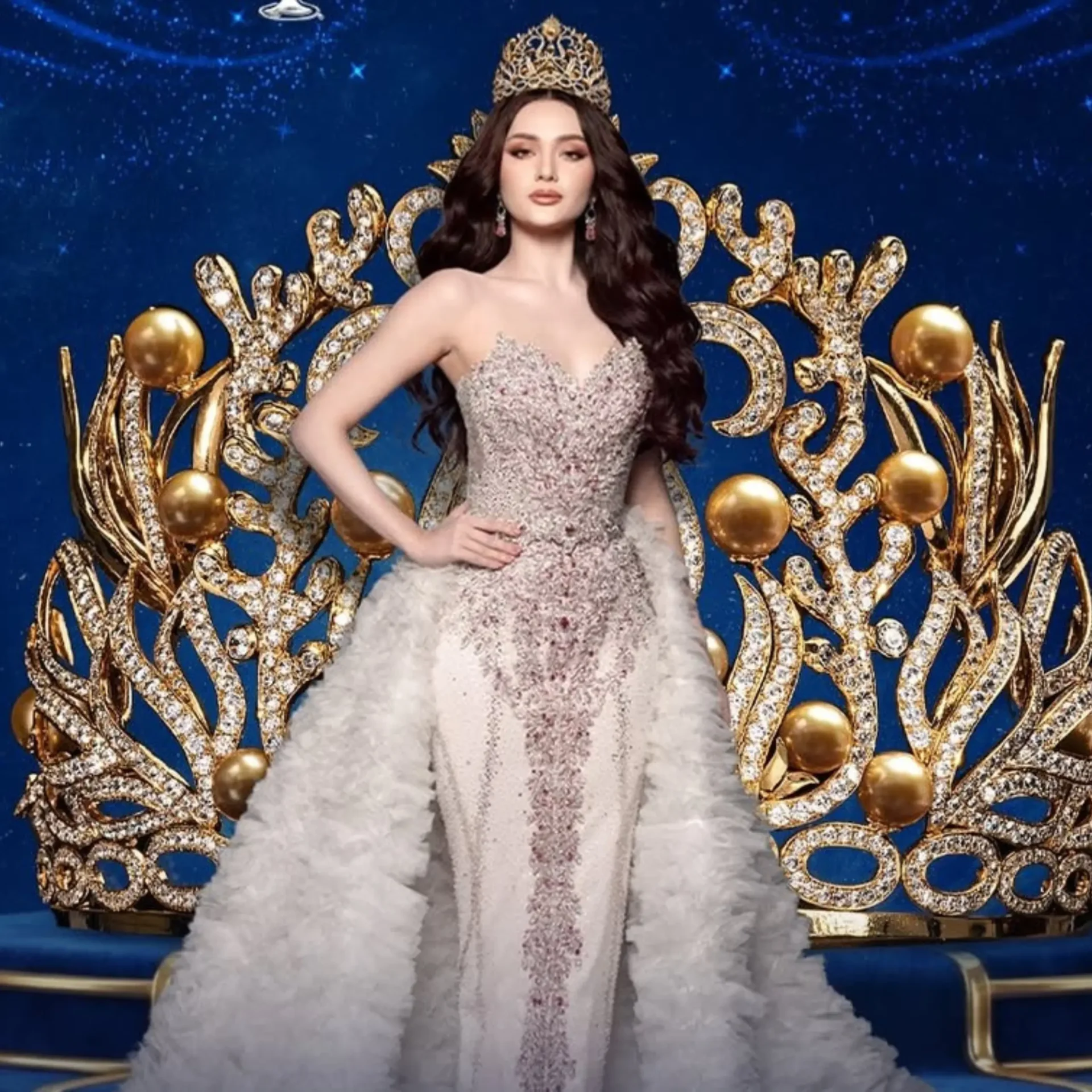 Royal figure seated on a glittering gold throne wearing a jeweled crown and gown against a blue starry backdrop.