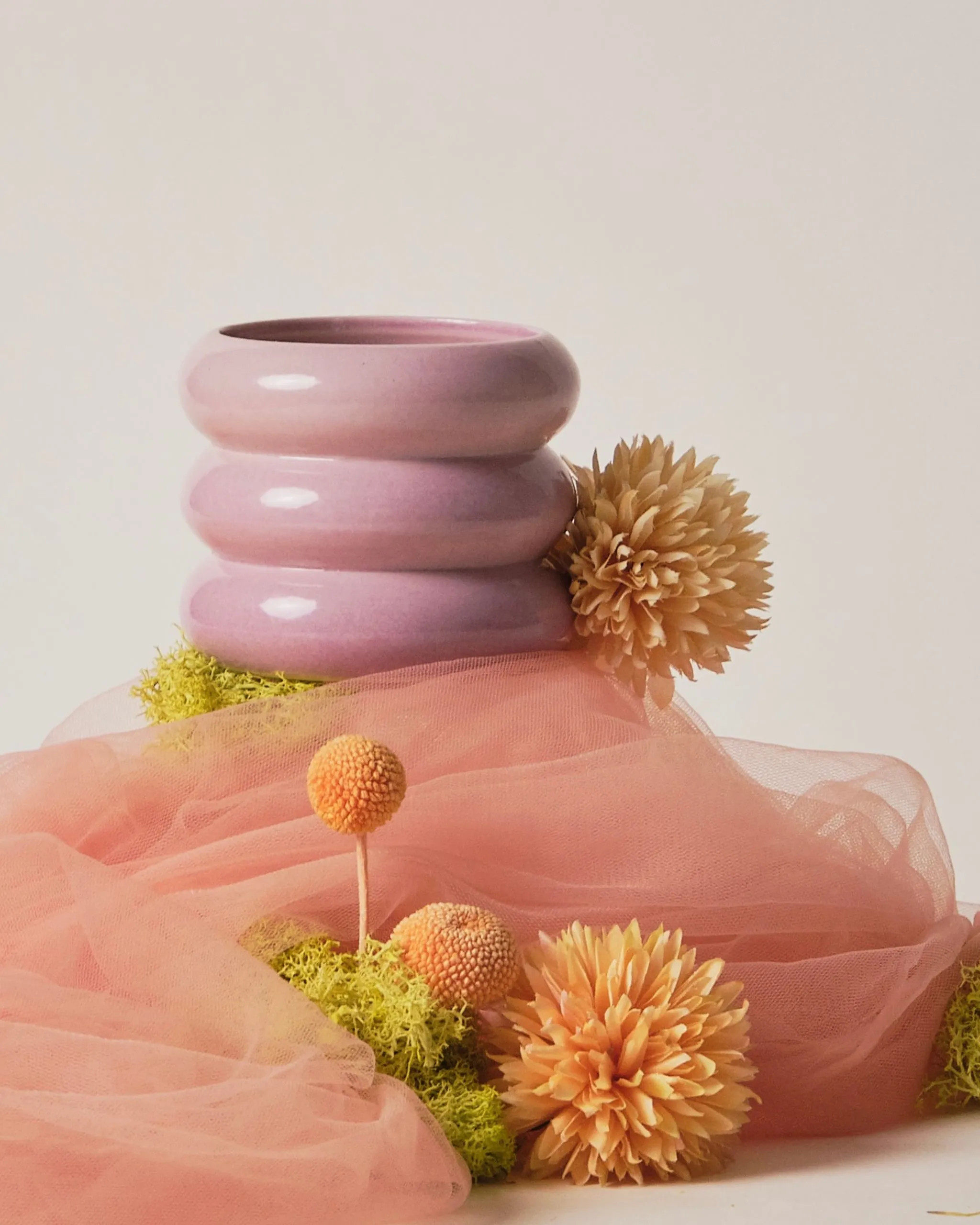 Pink stacked ceramic rings with soft pink tulle and peach dahlias forming a decorative arrangement.