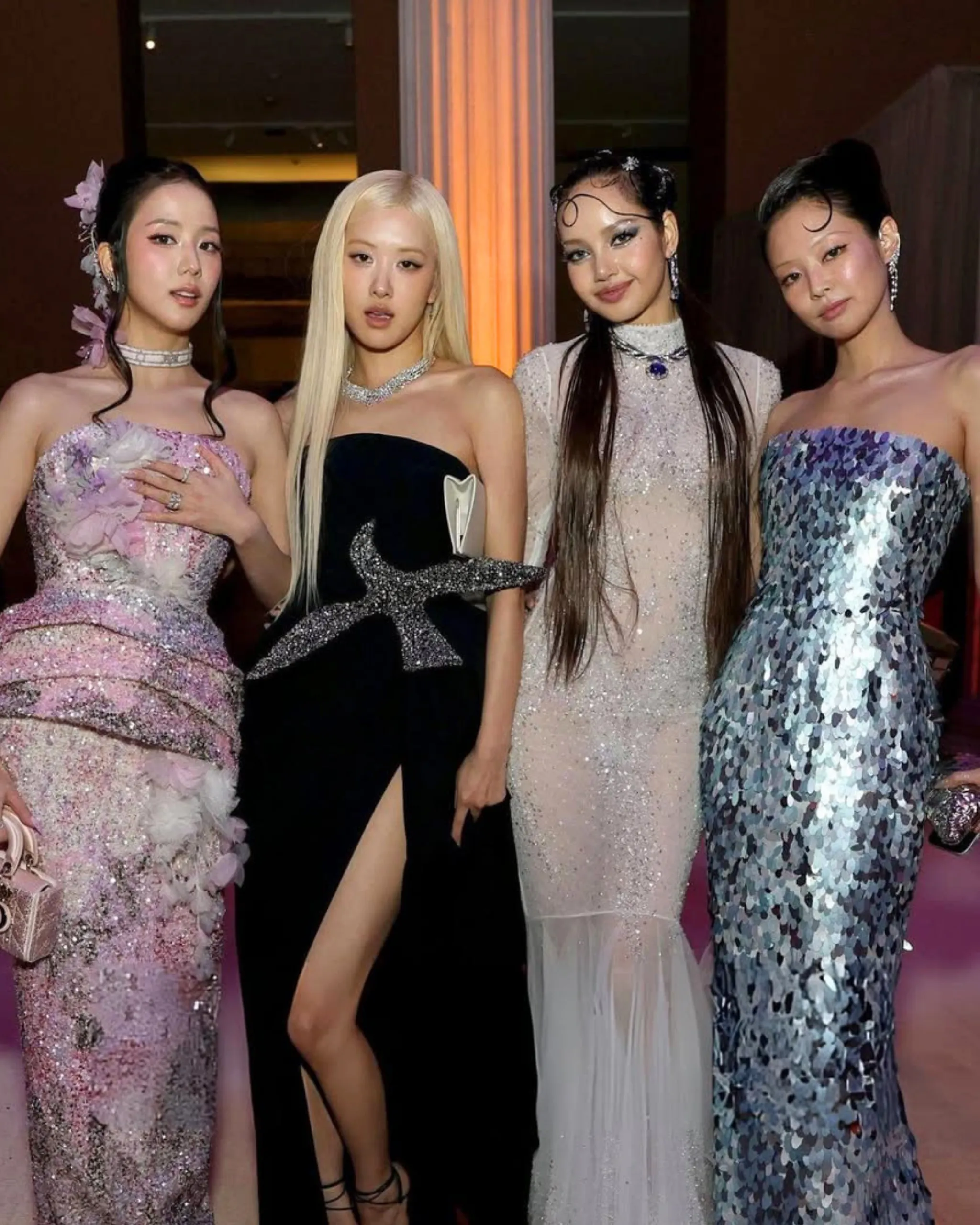 Four women in glamorous, sparkling gowns posing together at a formal event.
