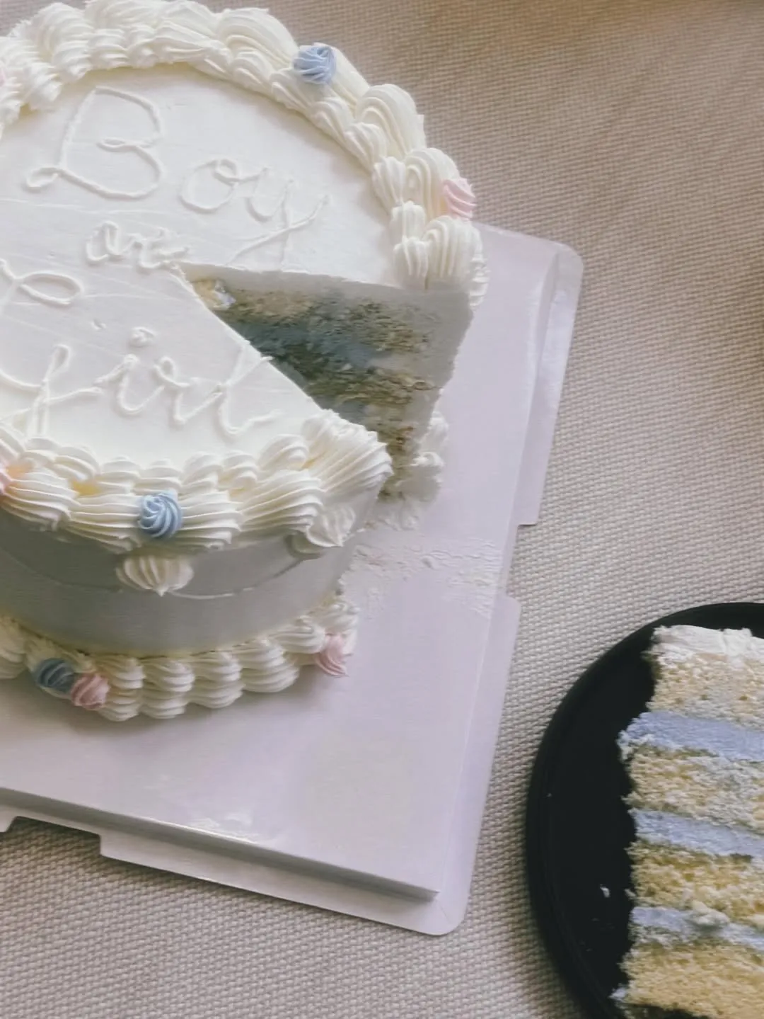 A white vintage-style gender reveal cake with a cut slice showing a blue interior, used by Celeste Cortesi to announce she is expecting a son.