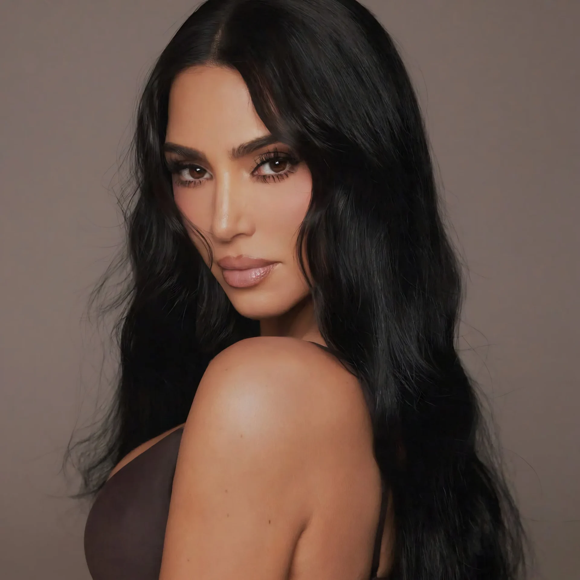 Close-up portrait of a woman with long black hair, showing her eyes and lips against a neutral brown background.