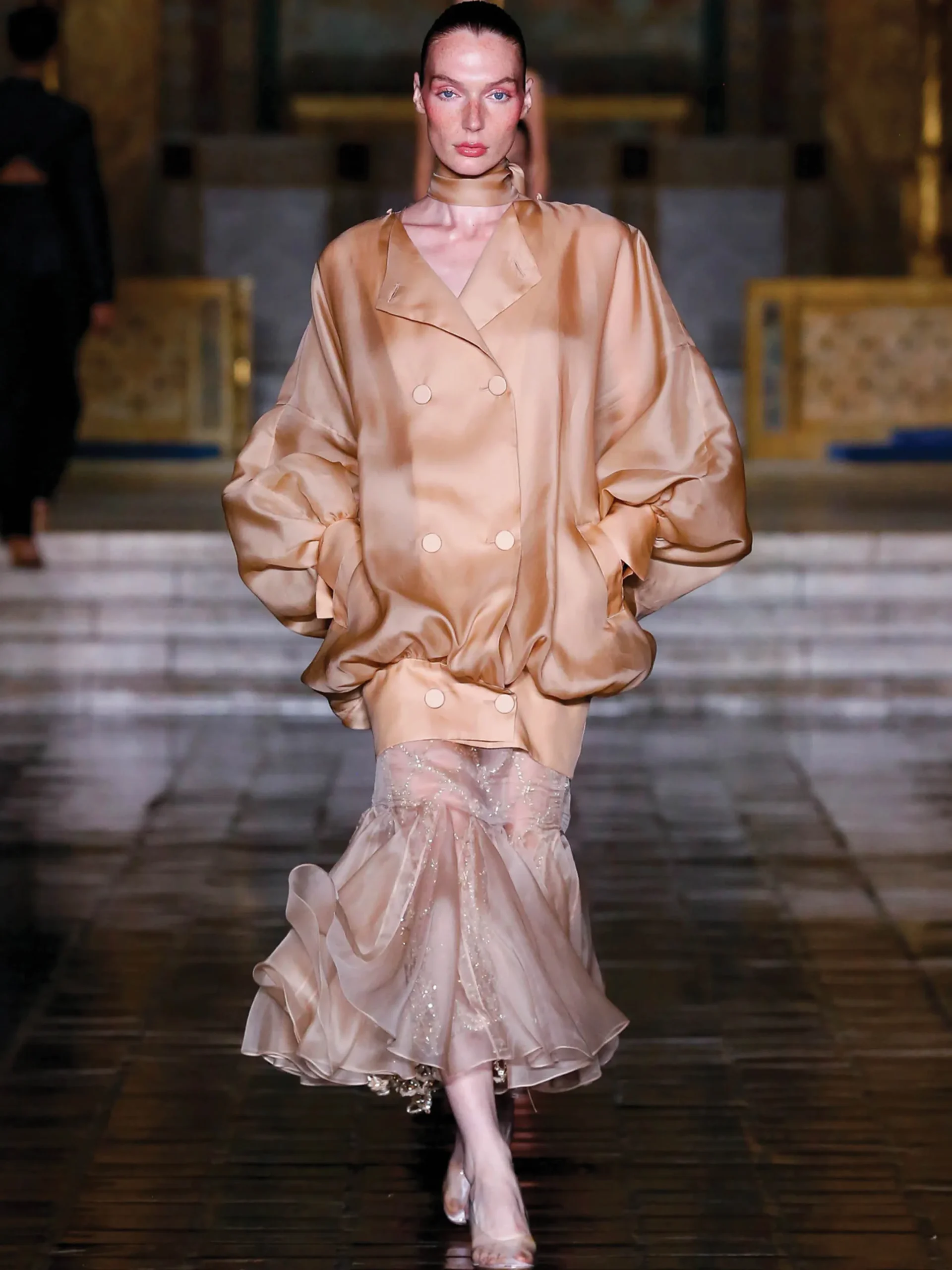 This model is showcasing a sheer, voluminous beige jacket paired with a coordinating frilled skirtfrom the Prabal Gurung Spring/Summer 2026 collection