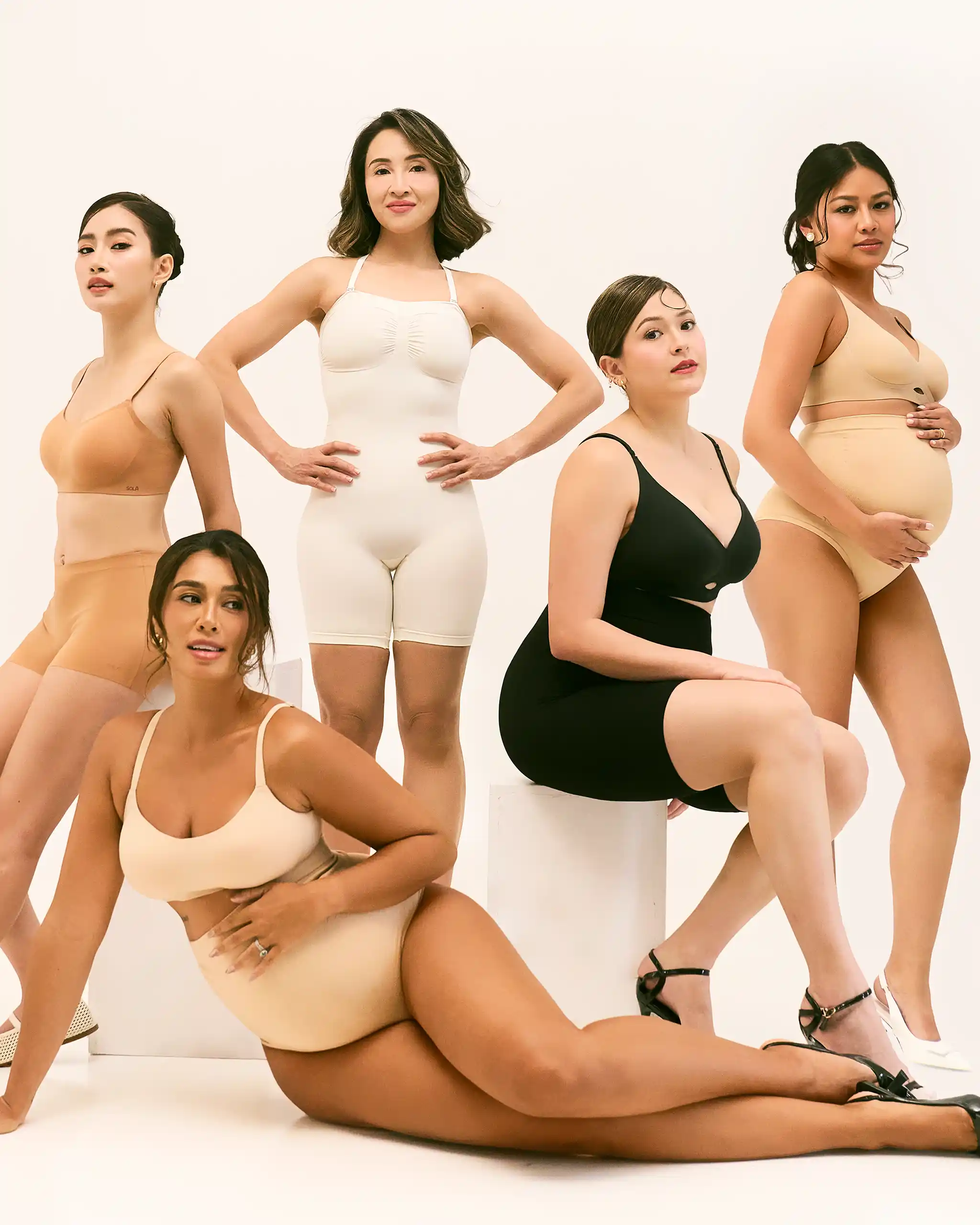 Group of diverse women posing in nude-toned lingerie against a pale backdrop, showcasing shapewear options.