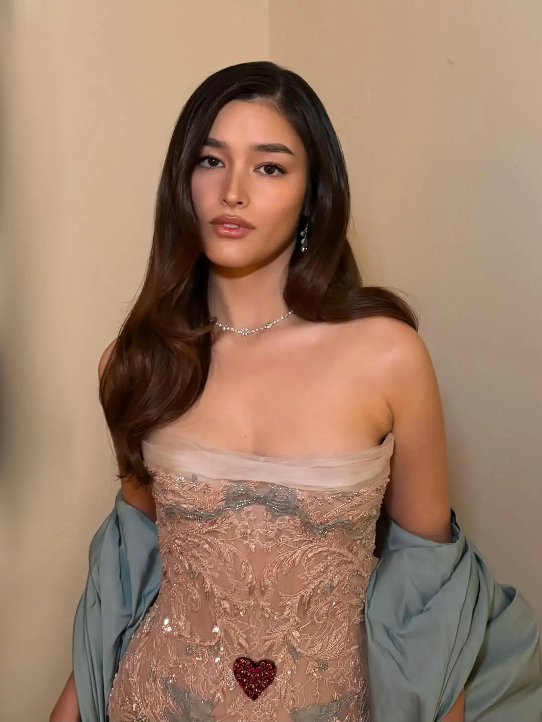 Actress Liza Soberano at the 53rd Annie Awards, wearing a custom strapless nude-beige lace gown adorned with intricate baroque embroidery, a small red heart embellishment at the waist, and a voluminous powder-blue wrap draped over her arms.