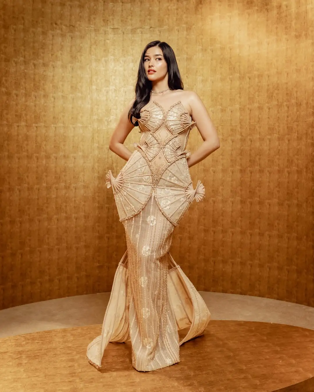 Actress Liza Soberano at the 2026 Gold Gala in Los Angeles, wearing a custom champagne gold mermaid gown by designer Phan Huy featuring structural Filipino pamaypay hand fan details.