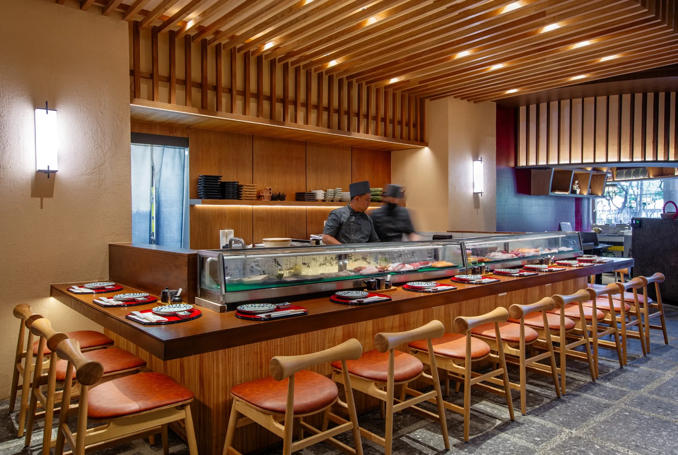 OGAWA BGC Wooden sushi-bar restaurant interior with chefs at the counter and a glass display case of sashimi.