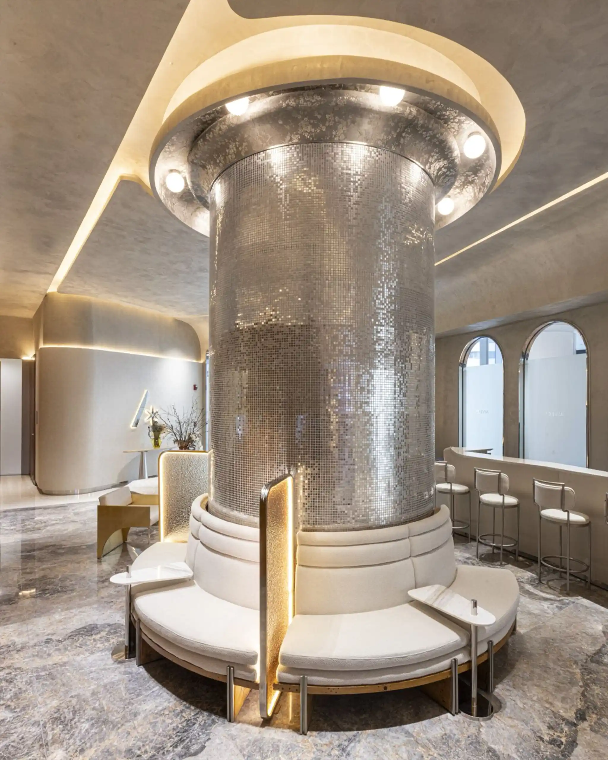 Central circular seating around a tall tiled column in a luxe lobby with marble floor and warm lighting