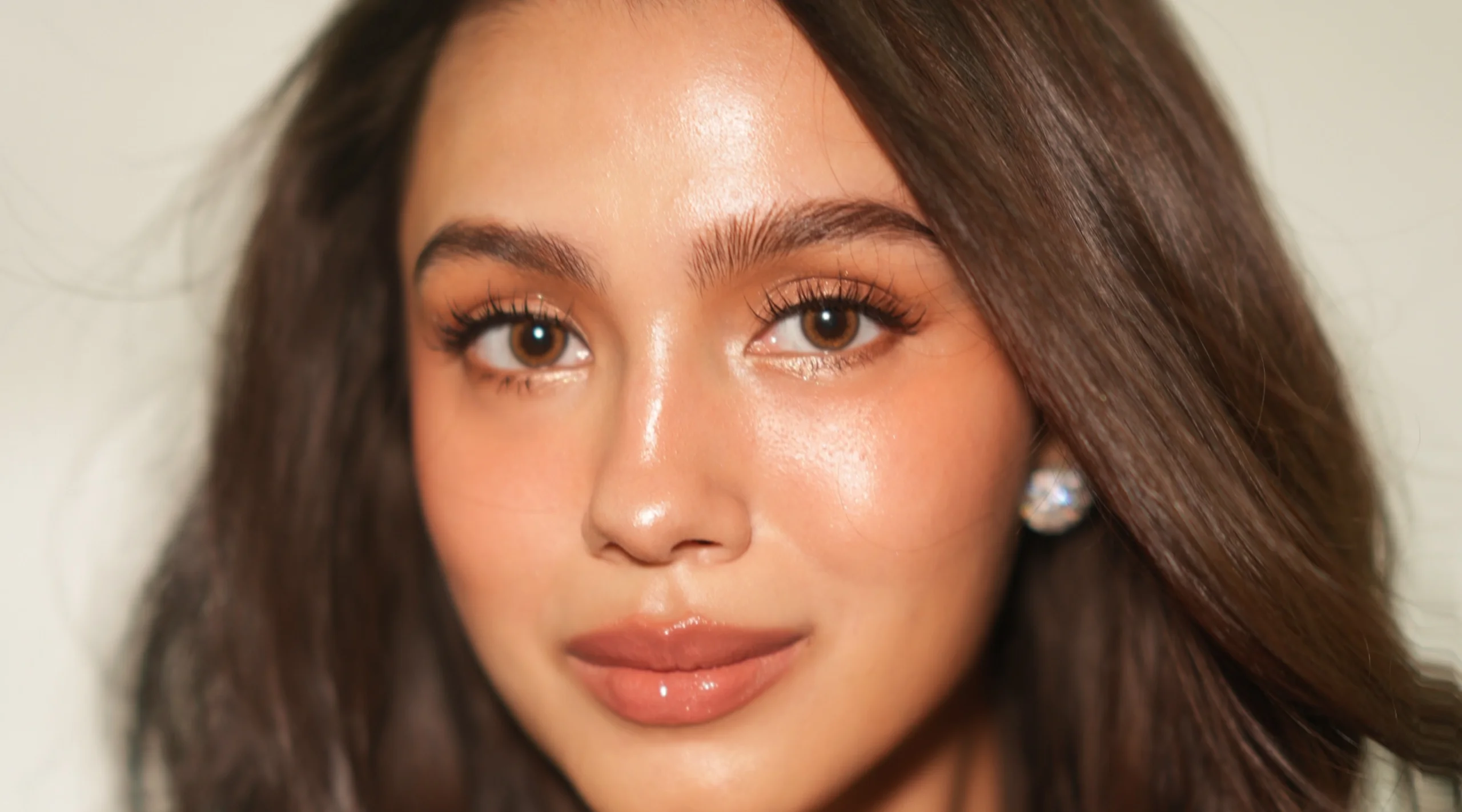 Close-up of a woman’s face highlighting brown eyes, long lashes, and glossy lips.