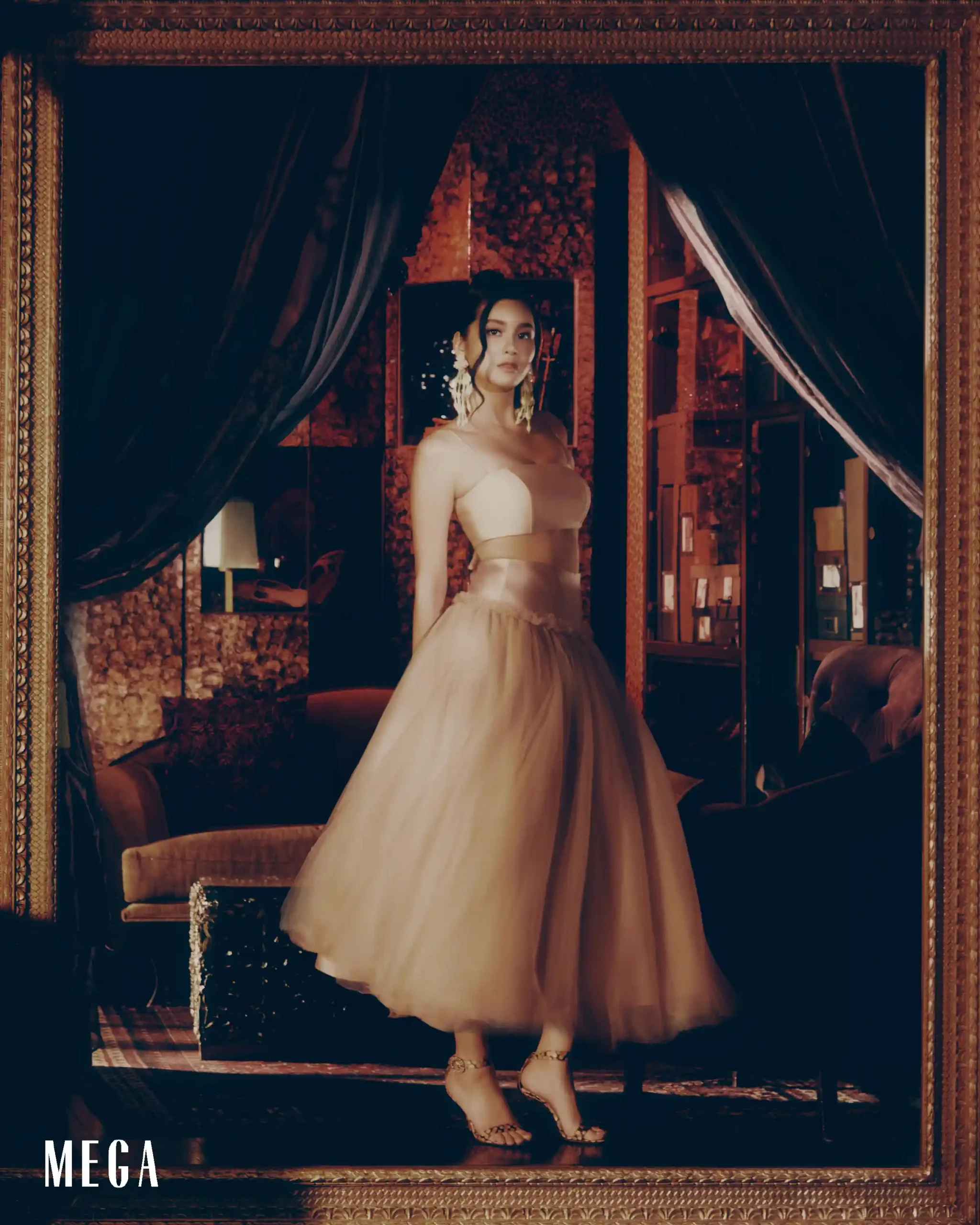Fashion model in a pale pink strapless gown stands inside a gilded frame on a fashion magazine cover (MEGA).
