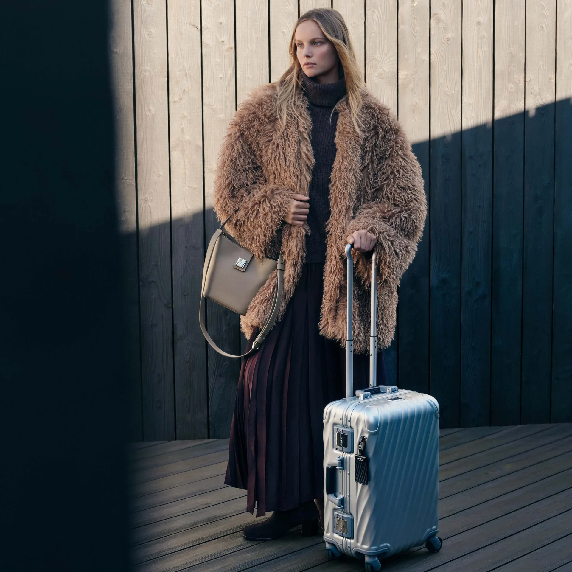 A traveling woman with her TUMI bag and carry-on